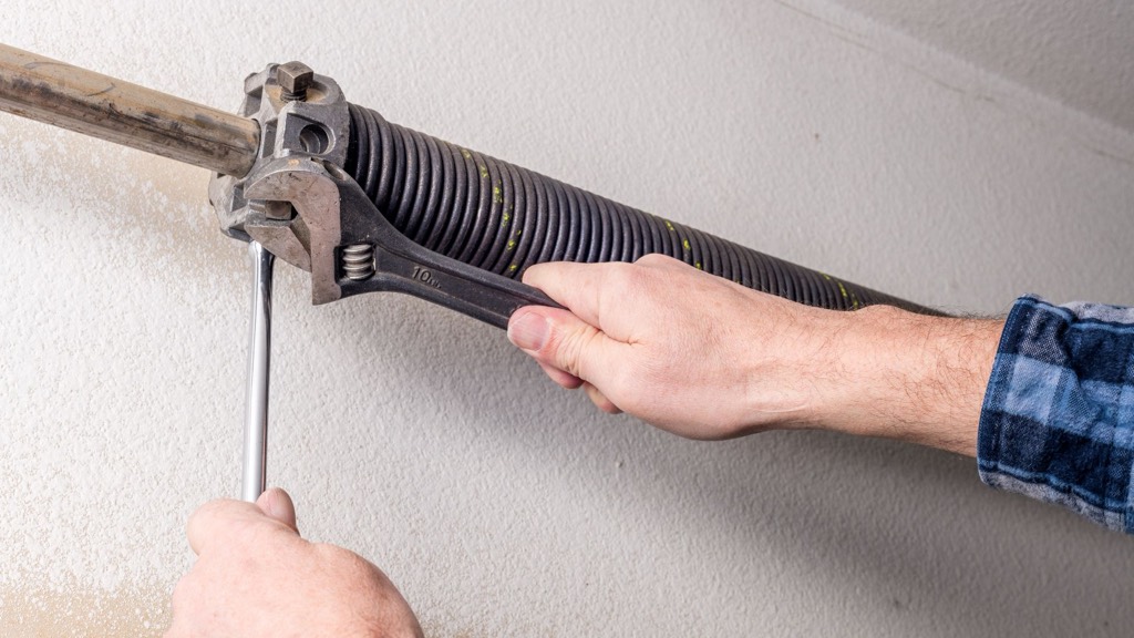 Technician inspecting garage door torsion springs and cables for winter wear in Cleveland